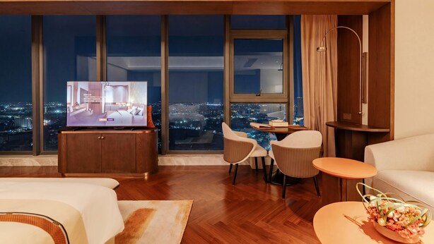 A modern hotel room with a large window, a television, a dining area, and a sofa. - Howard Johnson By Wyndham Phnom Penh Tk (Phnom Penh)