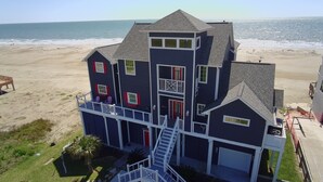 Una casa frente al mar de varios pisos, con balcón, escalera y vista al océano.
