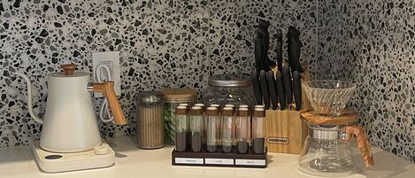A kitchen counter with a coffee maker, spice jars, a knife block, and a coffee dripper.