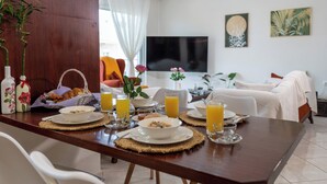 A dining table set with breakfast items, a TV, and a sofa in a living area.