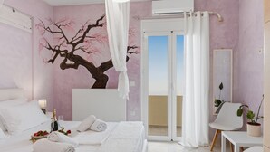A bedroom with a bed, a bedside table with a bottle and glasses, a chair, a potted plant, and a sliding glass door leading to a balcony.