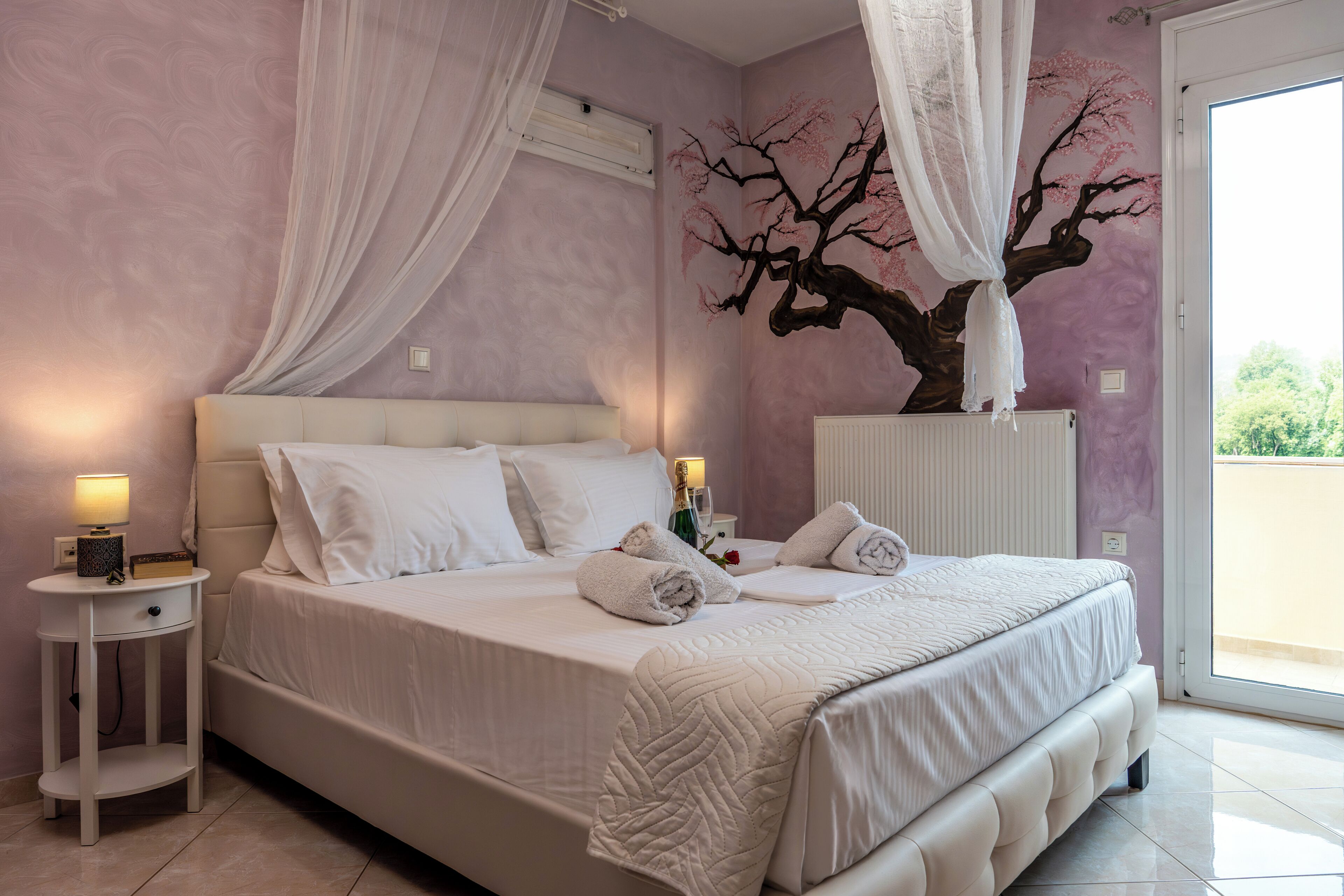 A bedroom with a bed, bedside tables, a nightstand, a canopy bed, and a wall mural.