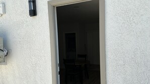 Ein Durchgang zu einem Raum mit einem Esstisch und Stühlen, einem Lichtschalter und einer Wandleuchte.