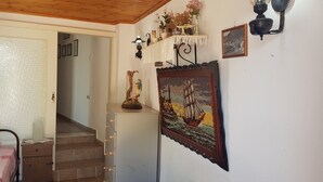 Een trap die leidt naar een slaapkamer met een bed, een klein tafeltje en een wandplank met decoratieve spullen.