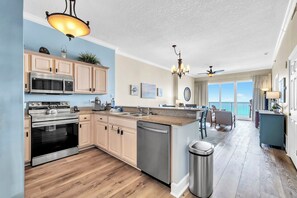 A modern kitchen with a built-in microwave, oven, and dishwasher, a dining area with a view, and a balcony with a view. - ☀️Stunning Gulf Front | 2 Pools + Hot Tub | Ocean Villa 2306☀️ (Panama City Beach)