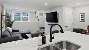 Una cocina moderna con una isla grande, televisor integrado y un área de comedor con sofá.