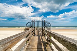 A wooden boardwalk leading to a beach with a metal gate. - St Augustine Beachfront Condo with Heated Pools (St. Augustine Beach)