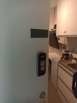 A kitchen with a built-in espresso machine, a small refrigerator, and a countertop with a sink. - Beautiful and recently built apartment in the Brooklin area. (São Paulo)
