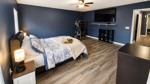 A bedroom with a bed, a desk, a TV, a ceiling fan, and exercise equipment. - Private Heated Pool + Spa Paradise Sleeps 9 (Seffner)