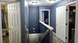 A hallway with a staircase, a door leading to a bedroom, and a closet with a coat rack. - Private Heated Pool + Spa Paradise Sleeps 9 (Seffner)
