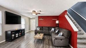 A living room with a sectional sofa, a coffee table, a TV, and a staircase. - Private Heated Pool + Spa Paradise Sleeps 9 (Seffner)