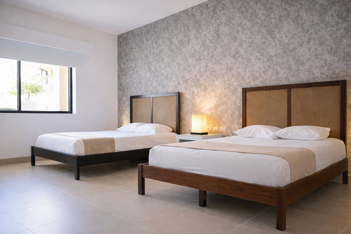 Une chambre d’hôtel avec deux lits, une grande fenêtre et un mur à motifs.