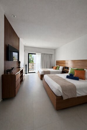 Ein modernes Hotelzimmer mit einem großen Bett, einem Fernseher, einer Holzkommode und einem Balkon mit Vorhängen.