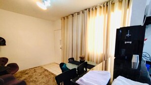 A hotel room with a dining table, chairs, a TV, and a sofa. - Modern Apartment in the South Zone (Uberlândia)