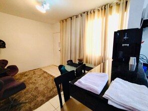 A hotel room with a dining table, chairs, a TV, and a sofa. - Modern Apartment in the South Zone (Uberlândia)