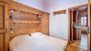 Une chambre à coucher en bois avec un lit, une table de chevet, une lampe et une tête de lit en bois.