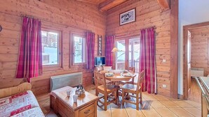 Une cabane en bois avec une table à manger, des chaises, un lit et un téléviseur.