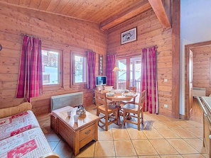 A wooden cabin with a dining table, chairs, a bed, and a TV. - 3rd floor, swimming pool, terrace, tv, ski locker, 32m², Les Menuires (Les Menuires)