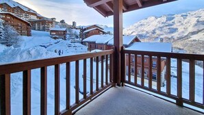 Un balcon avec vue sur une montagne enneigée et des bâtiments.