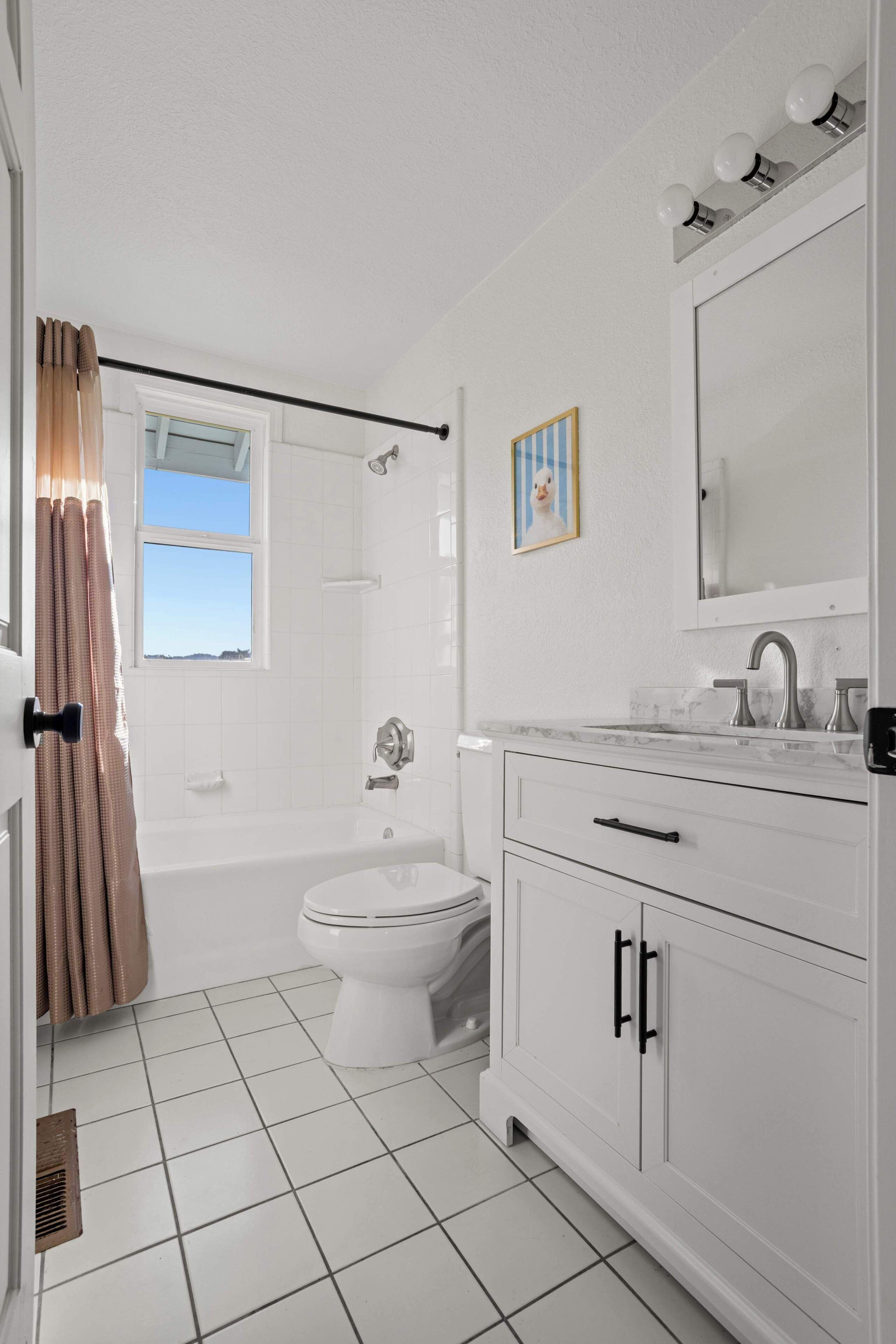 A bathroom with a bathtub, toilet, and vanity with a mirror and lights.