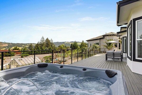 Un bain à remous sur une terrasse en bois, avec vue sur un quartier résidentiel.