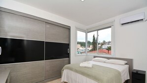 A bedroom with a bed, a window, a wardrobe, and a nightstand. - Apartamento na Trindade - CEN008 (Florianópolis)