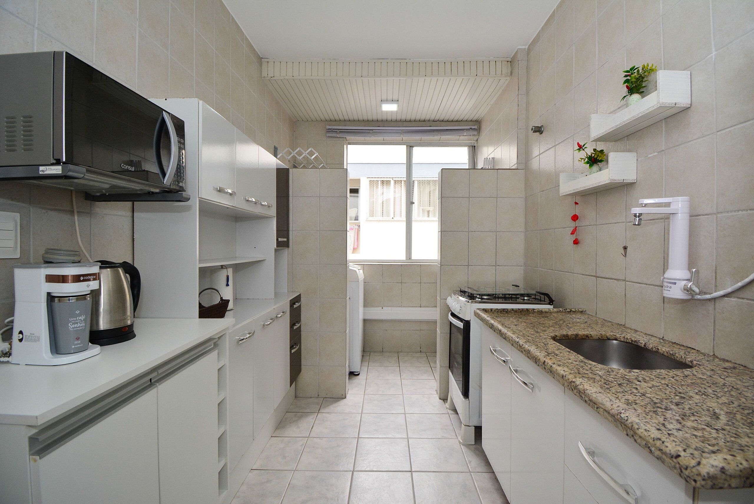 A compact kitchen with a microwave, coffee maker, oven, and granite countertop.