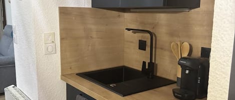 A modern kitchen with a black countertop, a sink, and a Bosch coffee maker.
