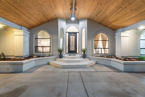 A spacious entrance with a wooden ceiling, a central door with a decorative glass panel, and two potted plants on either side. - The Four Peaks Palace - Luxury Desert Retreat (Fountain Hills)