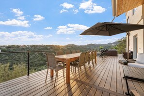 A wooden deck with a table and chairs, a large umbrella, and a view of a mountainous landscape. - The Four Peaks Palace - Luxury Desert Retreat (Fountain Hills)