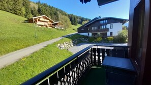 A balcony with a view of a rural road, a wooden house, and a modern building with a balcony. - 1st floor, balcony, tv, 32m², Les Gets (Les Gets)