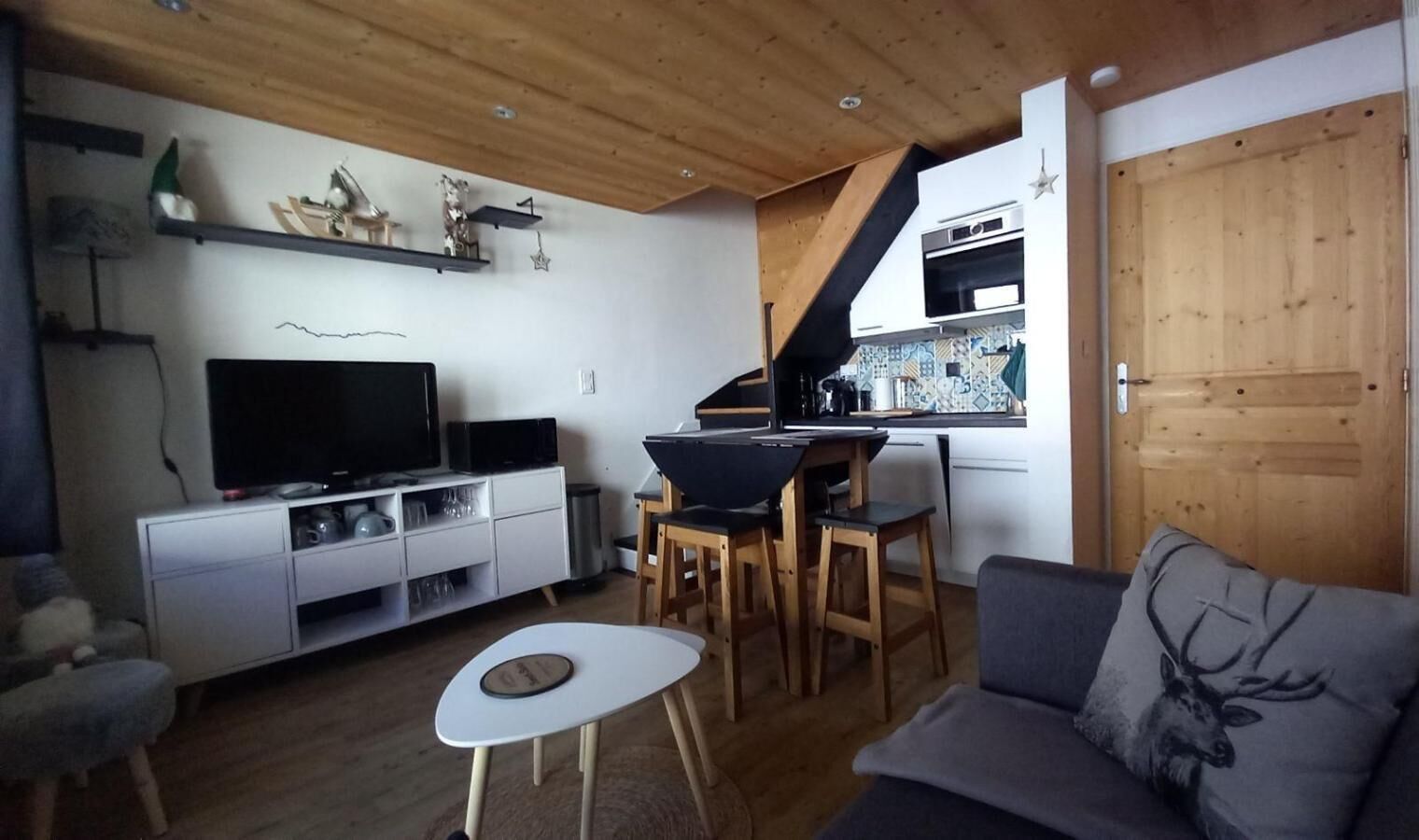 Ein gemütliches Wohnzimmer mit Fernseher, einer Couch und einem Essbereich mit Stühlen und Tisch.
