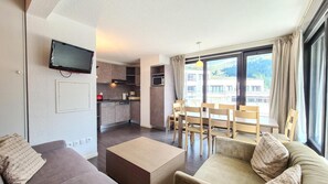 Eine moderne Wohnung mit Wohnzimmer, Essbereich, Küche und großen Fenstern.