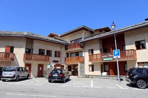 Ein mehrstöckiges Hotel mit Balkonen, einem Parkplatz und einem Schild, das ein Ziel anzeigt.