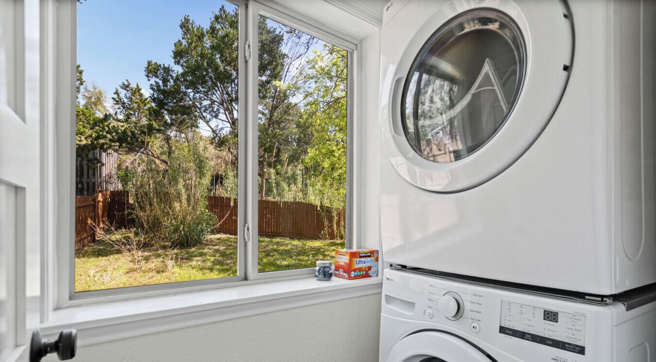 A front-loading washing machine with a window view of a backyard.