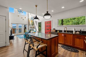 A modern kitchen with a large island, wooden cabinets, and a view of greenery outside. - Sunset Mountain Views · Hot Tub · Gated (Sevierville)