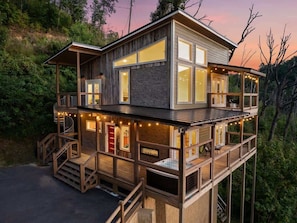 A two-story wooden house with balconies, a staircase, and string lights. - Heavenly Views Hot Tub Games Killer Design (Sevierville)