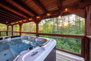 A hot tub with a wooden deck and a view of a forest. - Log Cabin Retreat | Spa+BBQ+Hammocks+Dogs+Games (Sevierville)