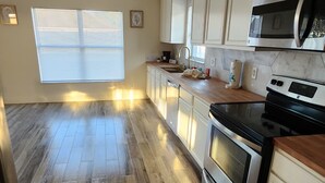 Une cuisine avec un plancher en bois, des armoires blanches, un four à micro-ondes et un four traditionnel.