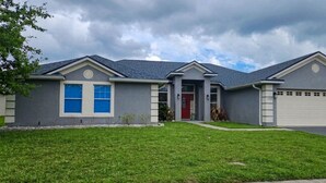Une maison d’habitation avec un garage, une porte d’entrée et une pelouse bien entretenue.