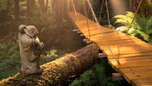 A wooden suspension bridge over a log, with a stone statue on the left.
