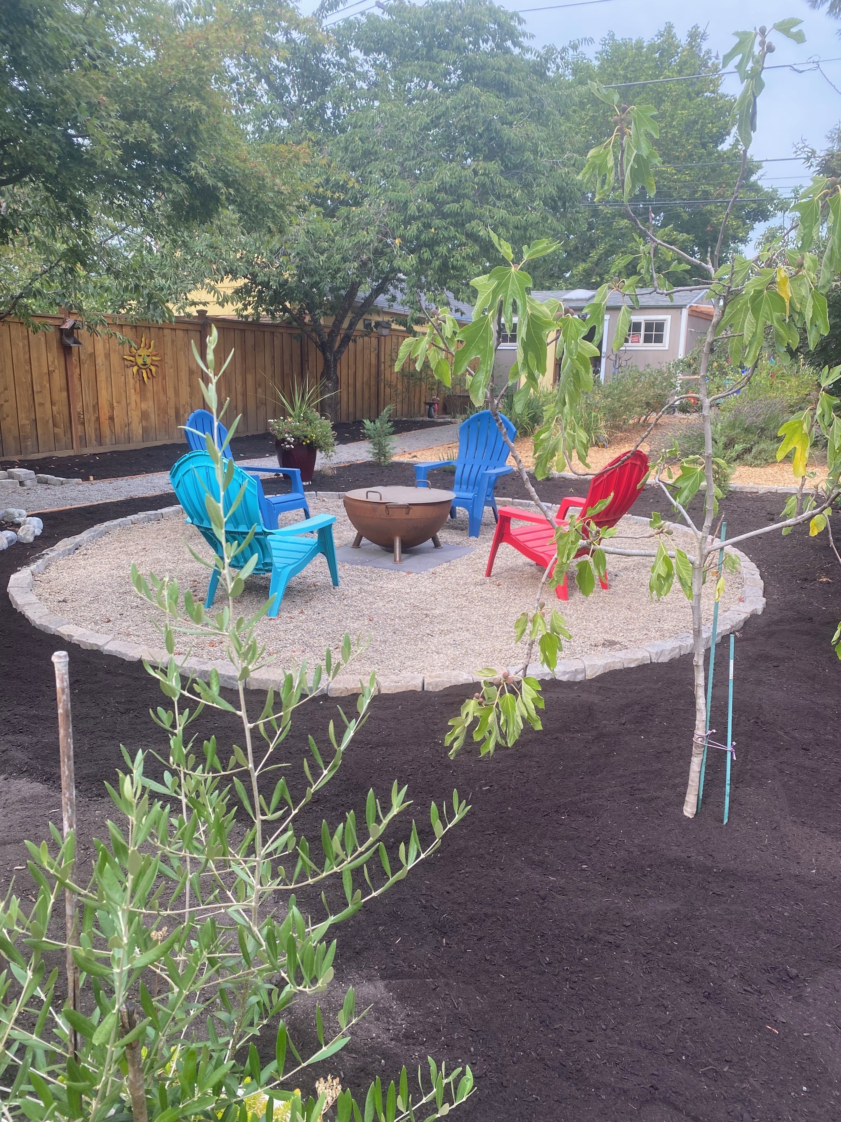 A backyard with a fire pit, outdoor furniture, and a wooden fence.
