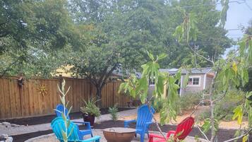 A backyard with a fire pit, outdoor furniture, and a wooden fence.