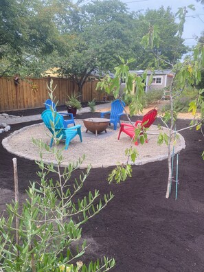A backyard with a fire pit, outdoor furniture, and a wooden fence.