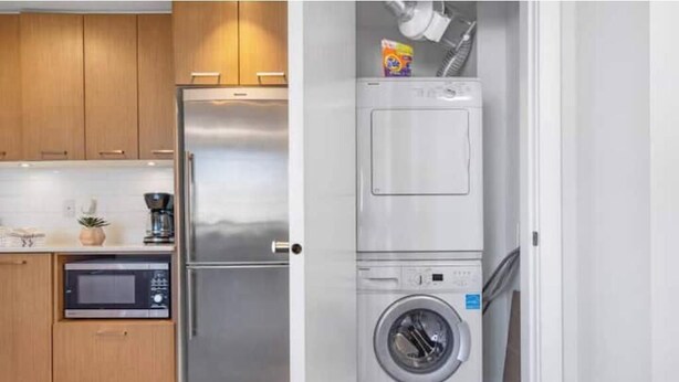 Una cocina compacta con un refrigerador de acero inoxidable, un microondas y una lavadora.