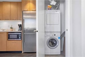 Eine kompakte Küche mit einem Edelstahl-Kühlschrank, einer Mikrowelle und einer Waschmaschine.