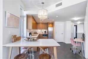 Une cuisine moderne avec des meubles en bois, un plan de travail blanc et un lustre.
