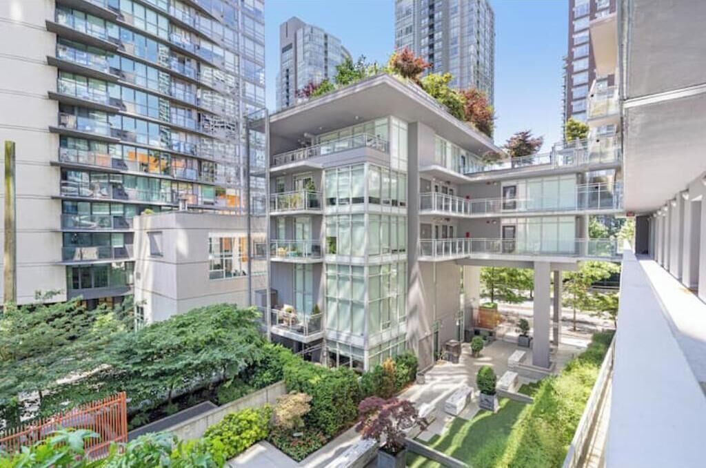 A modern high-rise building with multiple balconies, large windows, and a rooftop garden.