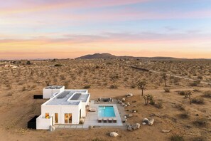 Uma casa moderna com piscina, emoldurada por uma paisagem desértica.