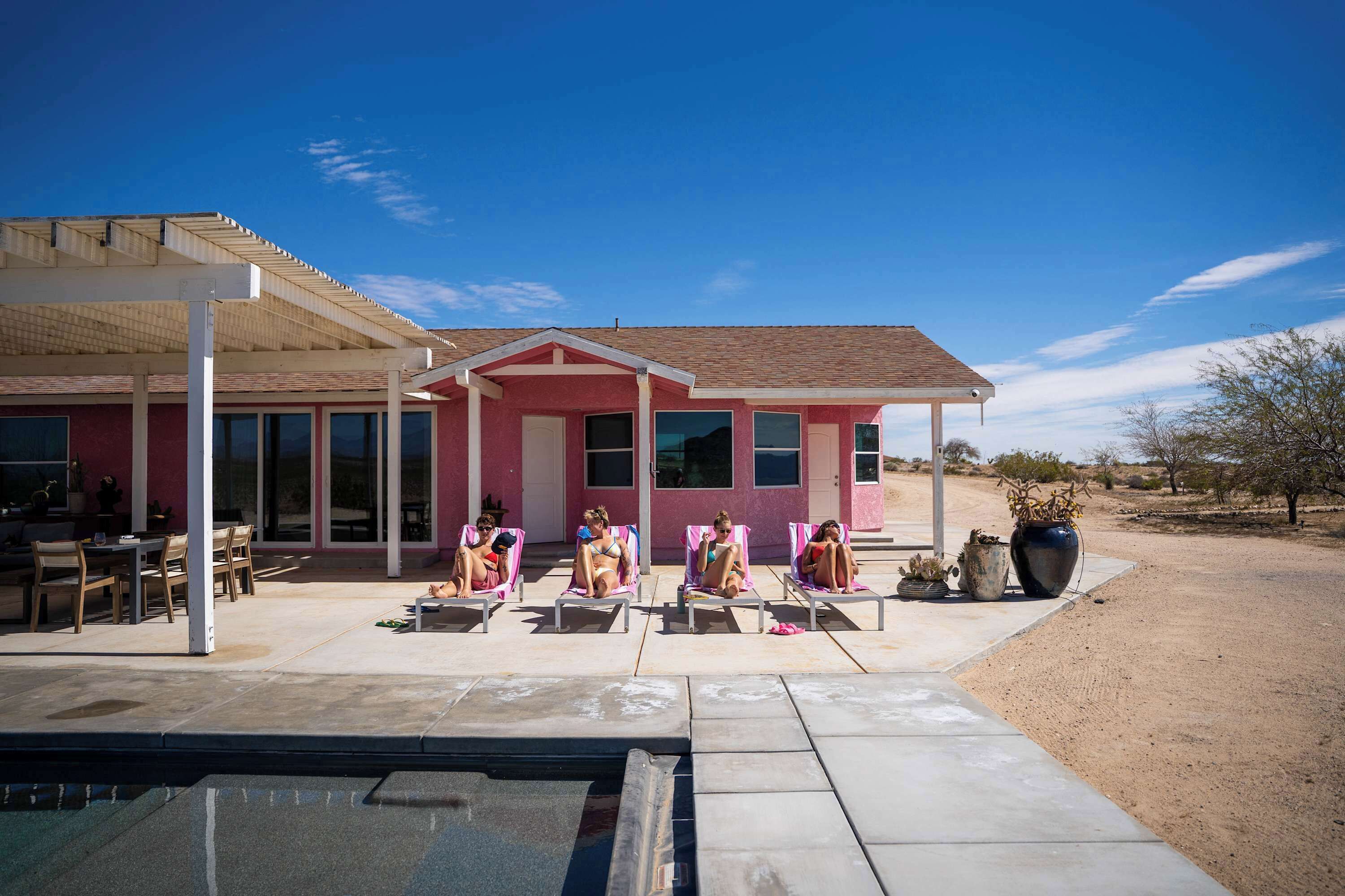 Ein Haus mit überdachter Terrasse, einem Schwimmbad und einer Wüstenlandschaft.